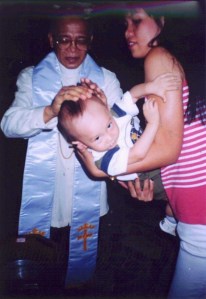 Despite trying to wriggle free, my son undergoes his baptism at a Methodist church in Manila, the Philippines.
